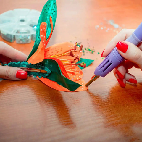 Using bedazzler kit with rhinestones and hot fix gems craft applicator to decorate a fabric flower with precision.