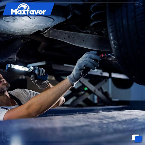 Mechanic inspecting car underside with light, focusing on areas like the front CV axle, in an automotive service garage.