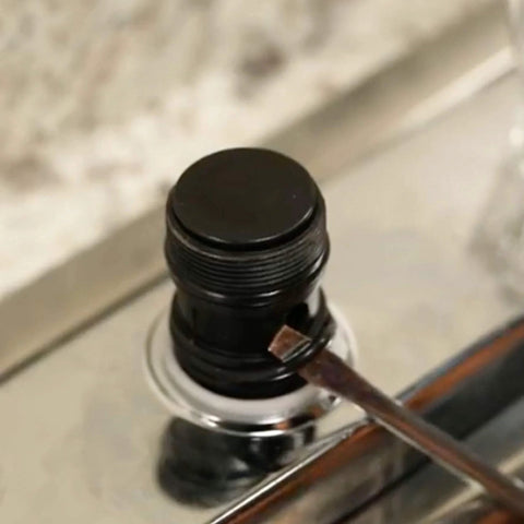 Faucet valve stem with black plastic cap on chrome faucet, close-up view