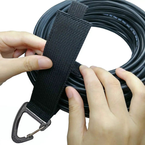 Hands using Extension Cord Holder Organizer 4 Pack Large 16 Inch Heavy Duty Storage Straps with Triangle Buckle for cable management.