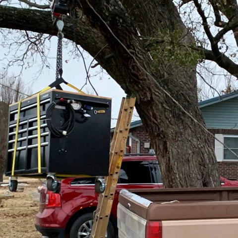 Lifting sling straps: yellow straps securing a black metal cabinet, front view.