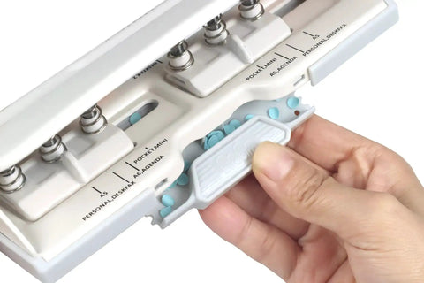 User adjusting an adjustable six hole punch for pocket journals and planners, 8 sheet capacity, fits mini and standard paper sizes from A3 to A6.