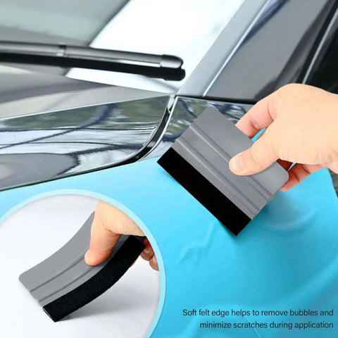 Using a felt squeegee from the Vehicle Vinyl Wrap and Window Tint Tool Kit for Car Wrapping DIY Pros on a car door panel.