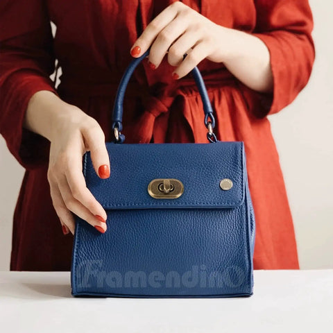 Woman in red dress holding a blue bag with antique bronze twist lock clasp, purse closure hardware visible on front.