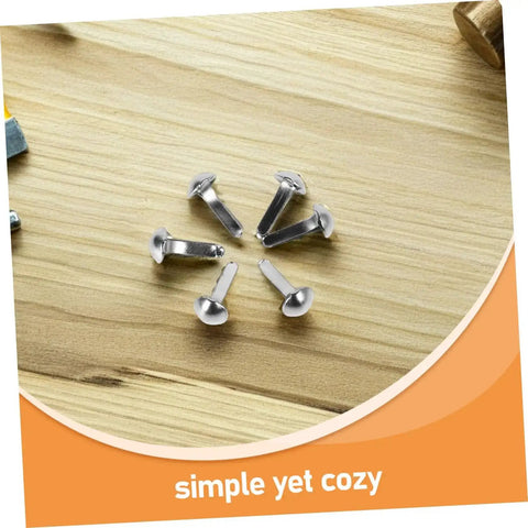 Shadow Puppet Accessories Kit With 100 Scrapbooking Brads And Paper Rivets Mini Iron Fasteners resting on wooden surface