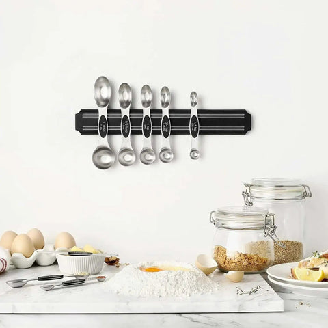 Magnetic Stainless Steel Measuring Spoons Set 8 Pieces With Leveler mounted on kitchen wall, surrounded by baking ingredients.