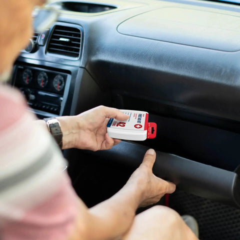 Person placing 500 Piece First Aid Kit Pack With 12 Individual Boxes for Comprehensive Wound Care in car glove compartment.