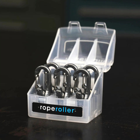 Front view of Roperoller 6-pack rope tensioners in a clear carry case; six black metal hooks, lid open.