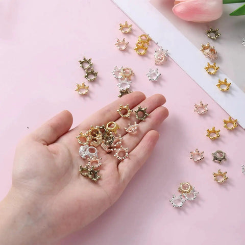 Hand holding 50 Pack Mini Crown Charms For DIY Jewelry Making, mixed color vintage 3D alloy king crowns, ideal spacer beads for crafts