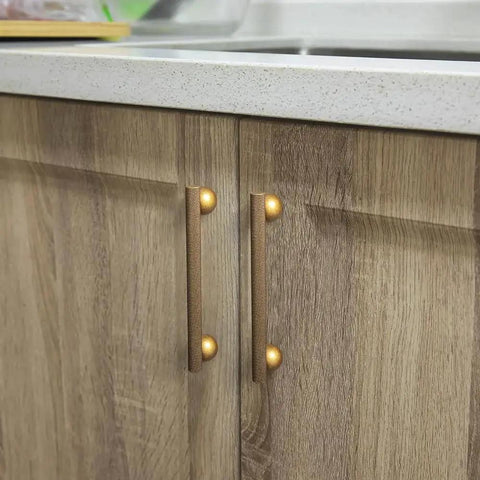Installed six pack 5 inch knurled antique brass bar pulls with round end mounts on wooden kitchen cabinets