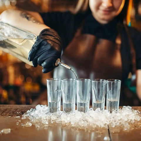Bartender wearing black nitrile exam gloves, pouring liquid into tall glasses on ice, Black Nitrile Exam Gloves Medium 4 Mil Powder Free Latex Free Food Safe Medical Grade Puncture Resistant 100 Count Box Ideal For Medical And Food Handling And Laboratory Use Suitable For Medical Dental And Food Service Environments