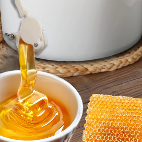HunterBee honey gate valve for 5-gal bucket, white plastic, pouring golden honey into a cup; honeycomb nearby.