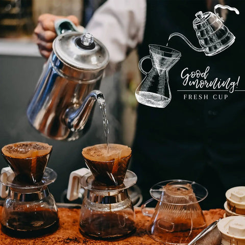Front view: two glass pour-over coffee carafes with cone filters and a metal kettle pouring hot water