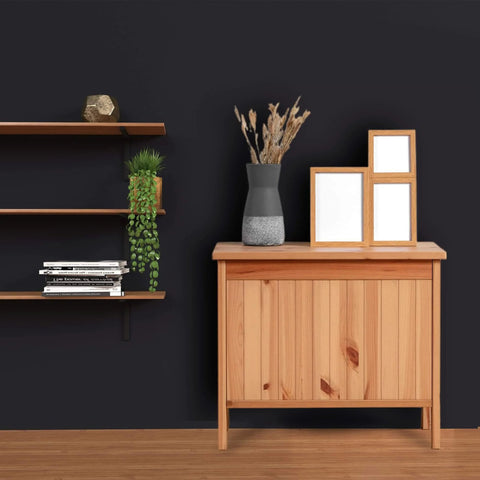 Wooden cabinet against black wall with decorative vase and frames, floating shelf with trailing plant and books