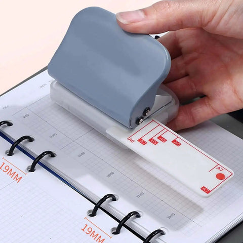 Using handheld 3 hole punch with metal construction and positioning ruler on a planner, 5 sheet capacity for B5 A4 A5 paper.