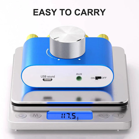 F900S 160W Mini Bluetooth 5.0 Power Amplifier on scale, showing lightweight design, front view with USB and AUX inputs visible