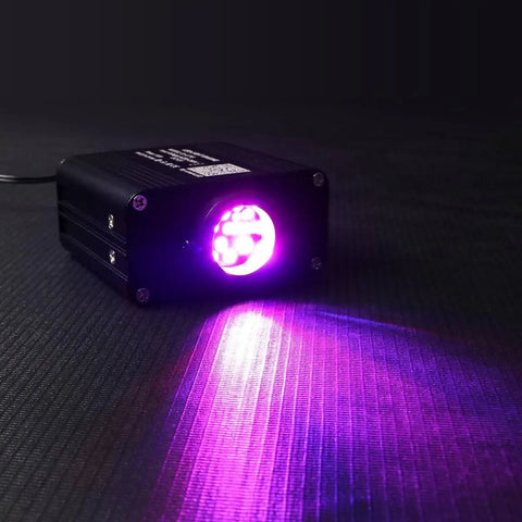 Compact 16W RGBW Fiber Optic Light Engine With Twinkle And Sound Activated Modes on black surface, purple light beam