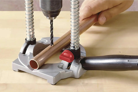 Multi Angled Drill Guide Attachment For On Site Drilling And Woodworking For One Quarter Inch And Three Eighths Inch Drills, Adjustable Up To Forty Five Degrees With A V Channel Base That Grips Curved Objects Up To Three Inches in use drilling a copper pipe