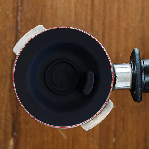 Top-down view of 54mm espresso backflush cleaning disc, black plastic, inside a portafilter