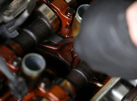 Close-up of a mechanic using a Two Piece Tapered And Offset Feeler Gauge Set With 32 Dual Marked SAE And Metric Blades And 16 Offset Dual Marked Blades For Tight Spaces To Precisely Measure Mechanical Clearances In Automotive And Machine Shop Jobs Pro Grade in an engine.