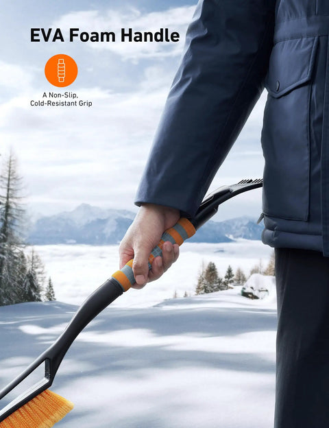 Person using 27 Inch Snow Brush With Detachable Ice Scraper And Ergonomic Foam Grip For Cars Trucks And SUVs Heavy Duty ABS PVC Bristle Brush Orange in snowy landscape.