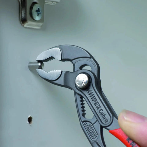 Cobra Water Pump Pliers, 5 Inch, Red, Adjustable Pliers With Self-Locking Teeth, used on a pipe for grip during installation.