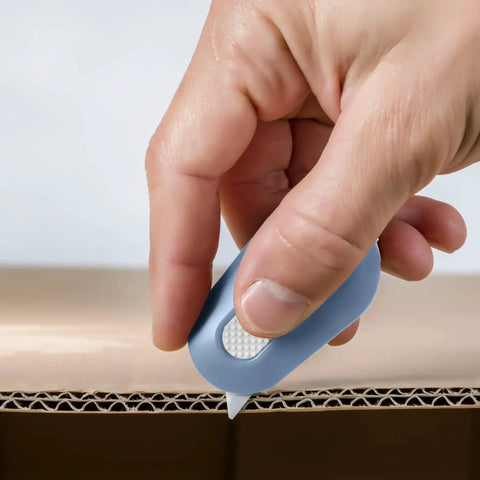 Hand holding a Manual Retracting Ceramic Box Cutter With Safe Edge For Packaging cutting cardboard