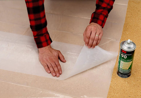 Applying laminate with Hi-Strength Spray Adhesive 90, Low VOC 14.6 oz can, CARB compliant, alongside adhesive can on a cork surface