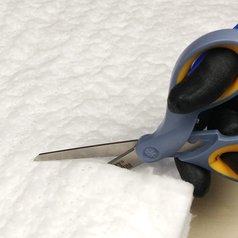 Ceramic fiber insulation blanket being cut with scissors; 1/4 in thick, 16 in x 240 in, white.