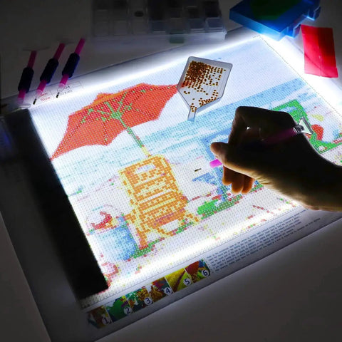 Diamond Painting Light Pad Kit A4 With LED Tracing Box And 5D Tool Set in use for a partial drill art scene, hand applying diamonds
