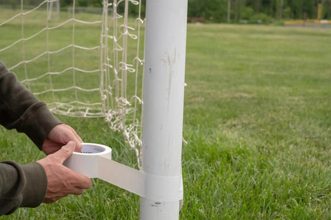 Person using White Duct Tape Roll 1.88 Inch By 20 Yards Heavy Duty For Repairs Crafting And Temporary Floor Marking Removable Cleanly Up To Three Weeks Not For Hardwood Or Direct Sunlight Single Roll on a soccer post outdoors.