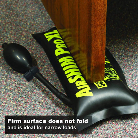 Air Shim Pro inflatable leveling wedge under wooden table leg, front view with hand-pump bulb on carpet.