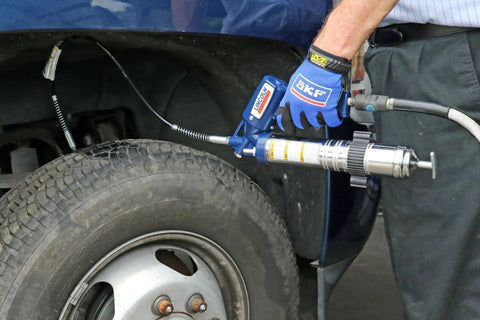 Grease gun, Lincoln 1142 lever-action, blue metal body with 6-inch extension and hydraulic coupler, in use on tire