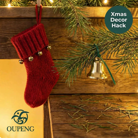 Red Christmas stocking with bells hanging on wooden ledge next to evergreen branch with silver bell decoration.