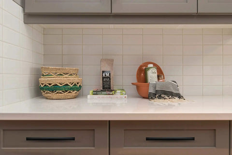10 Pack Curved Matte Black Cabinet Pulls on kitchen drawer under countertop with decorative items.