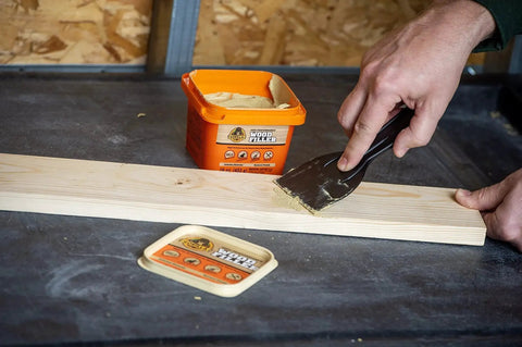 Applying All Purpose Wood Filler Natural Finish 16 Oz Water Resistant Indoor Outdoor Use on wooden plank with putty knife