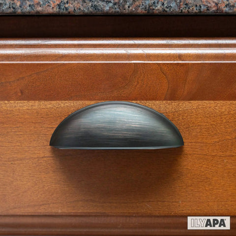 Oil Rubbed Bronze Cabinet Cup Pulls Three And A Half Inch Overall Length 10 Pack Durable Drawer Handles installed on wooden cabinet.