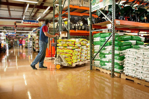 Person using a Hand Pallet Jack 5000 Lb Capacity With Roller Entry And Exit Ramp Tapered Fork Tips No Maintenance Sealed Bearings in warehouse.