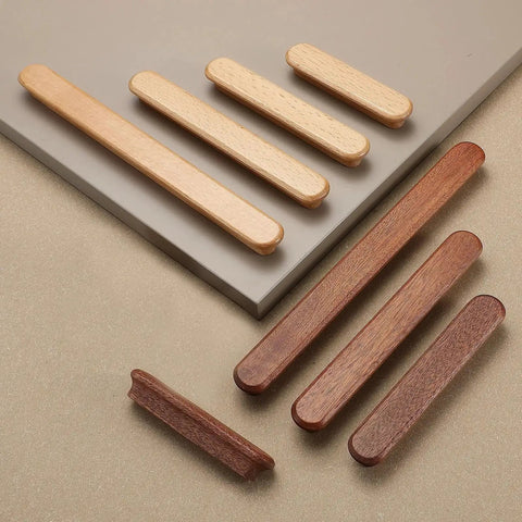 Various wooden drawer knobs and handles on display, showcasing different wood tones and styles on a neutral background.