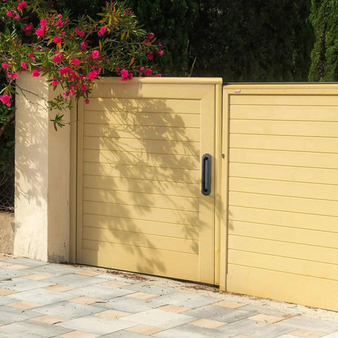 Beige sliding gate with a black handle installed on a sunny day.