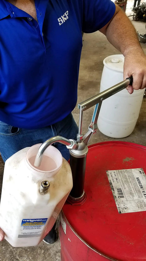 Guardian Lever Action Drum Transfer Pump for 16 to 55 Gallon Drums with 2 Inch Bung and Bushing in use, transferring liquid from red drum
