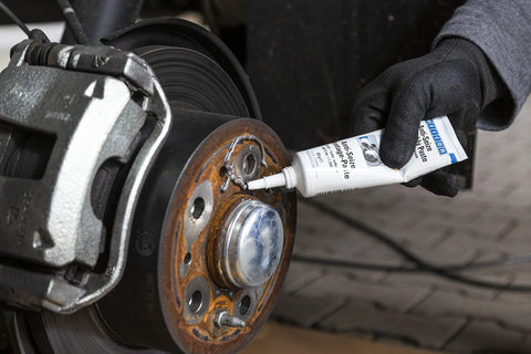 Applying Anti-Seize Assembly Paste, 3.0 Oz, Heat Resistant Lubricant and Corrosion Protection for fasteners on a car brake assembly