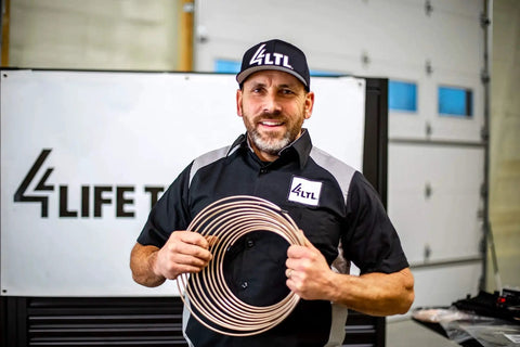 Copper-nickel brake line tubing coil held by a mechanic in a workshop.