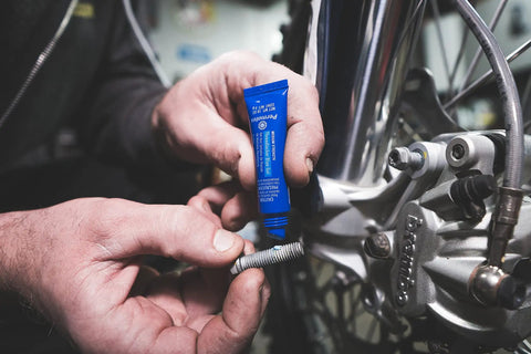 A person applying Blue Medium Strength Threadlocker That Eliminates Vibration No Drip Seals Leaks Prevents Rust And Disassembles Without Cracking Or Shrinking Permatex 27 070 6 Ml to a metal bolt during repair.
