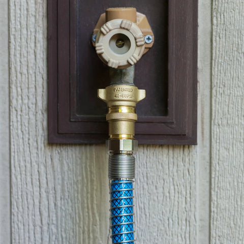 Camco brass RV water pressure regulator with blue braided hose mounted on exterior wall; 40-50 PSI