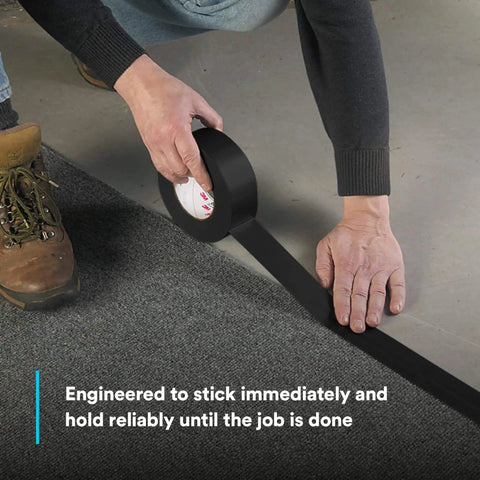 Person applying Extra Heavy Duty Industrial Duct Tape 6969, Gray, to carpet. Size 48 mm x 54.8 m, aggressive rubber adhesive.
