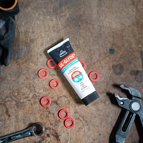 Sil-Glyde Multipurpose Lubricant 4oz Tube For All Surfaces, Weatherproofing Power on a workbench with tools and rubber rings.