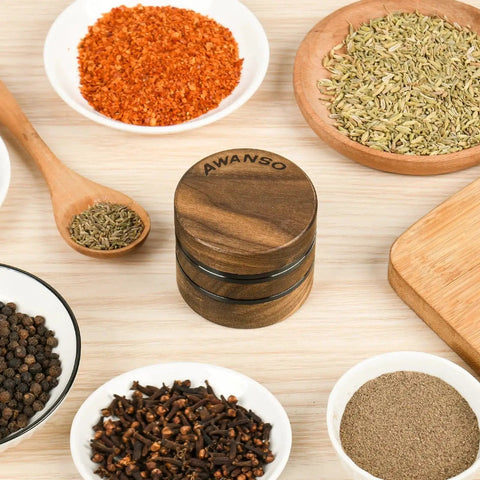 Walnut Wood 2.5 Inch 3 Piece Spice Grinder With Aluminum Chamber Magnetic Lid Raised Storage Base No Screen Easy To Clean For Kitchen Spices Pro Tip Flip For Finer Grind on a table with various spices