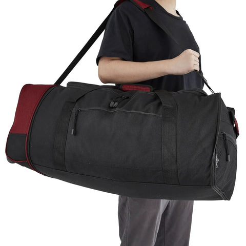 Person carrying black and red Expandable 32 Inch Rolling Travel Duffel Bag in Red by Travelers Club With Inline Blade Wheel System