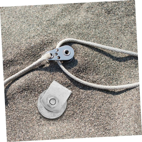 Close-up of a metal pulley and rope on sand, related to Beefy Heavy Duty Cast Iron V Groove Wheel Pulley For Sliding Gates And Garage Doors.